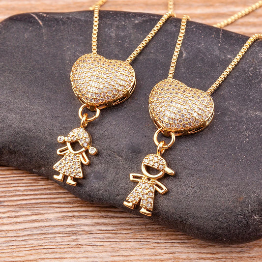 Gold heart-shaped pendants with child and baby charms on a stone surface