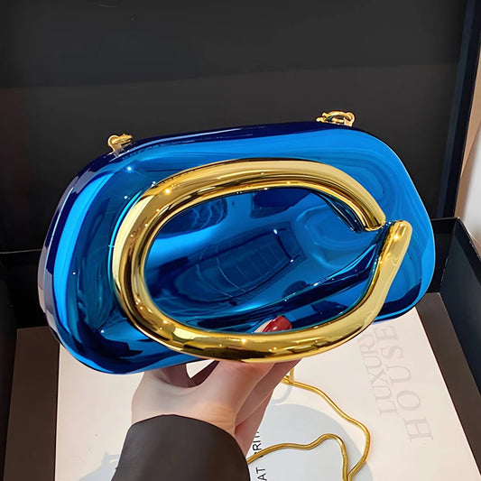 Blue handbag with gold handle held by a person on a white surface.