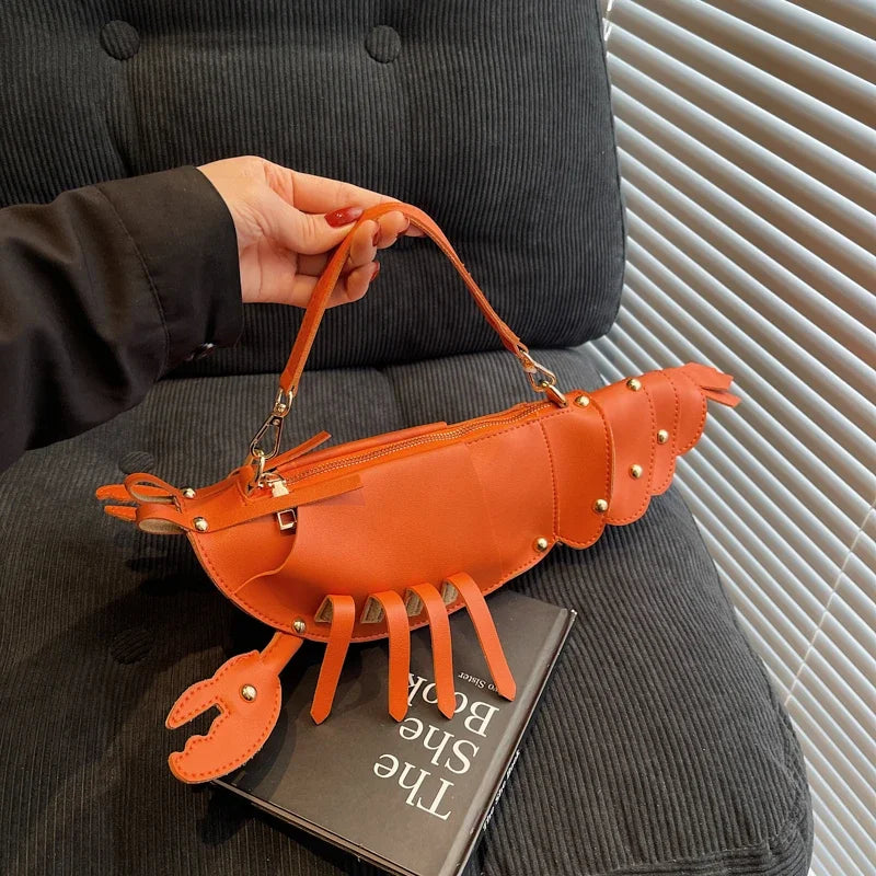 Person holding an orange lobster-shaped handbag with a book underneath.