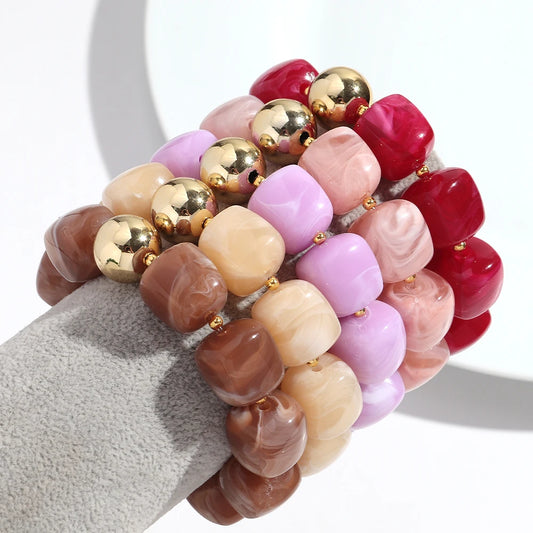 Set of colourful beaded bracelets on a grey surface with a white background