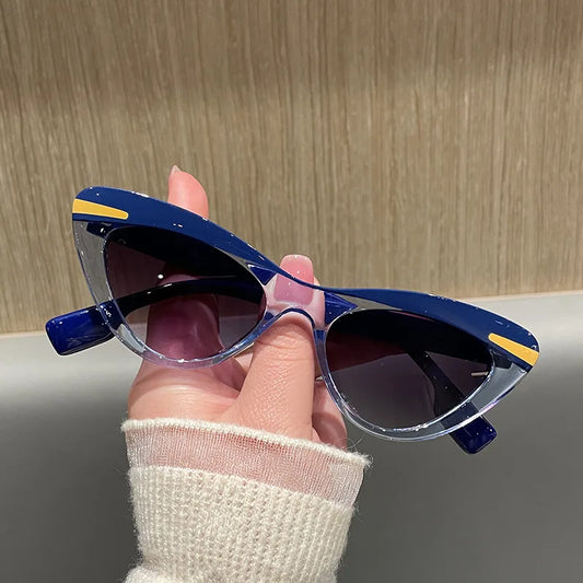 Hand holding a pair of blue sunglasses with yellow accents against a neutral background