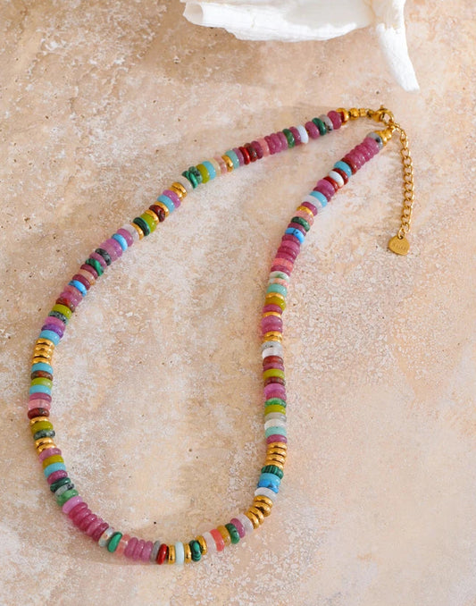 Colourful beaded necklace on a textured beige surface.