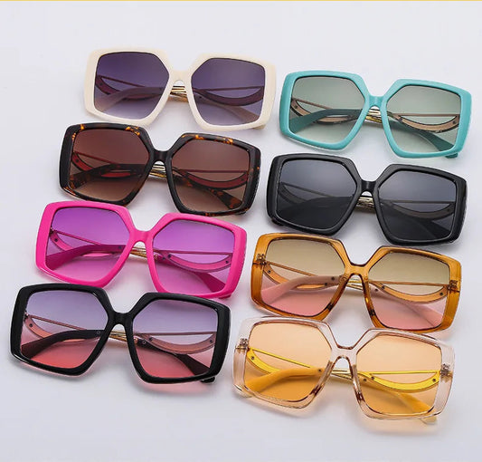 Six pairs of oversized square sunglasses in various frame colours and lens shades, arranged on a white background .