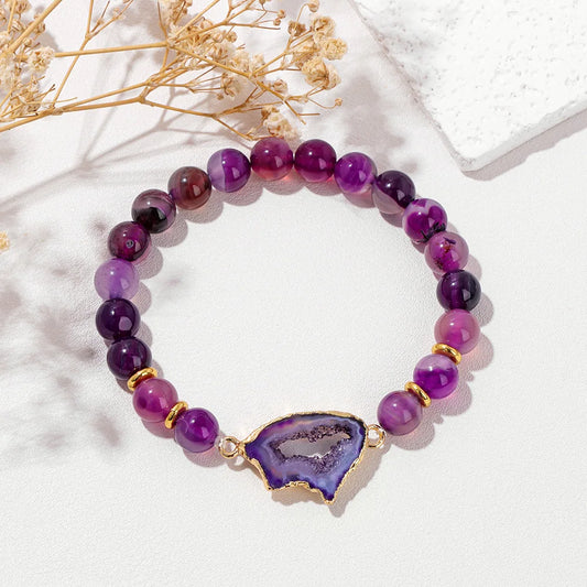 Purple beaded bracelet with a purple geode charm on a white background