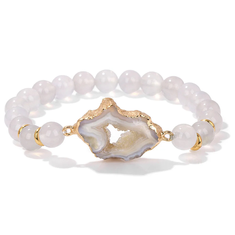 Bracelet with white beads and a gold agate slice charm on a white background