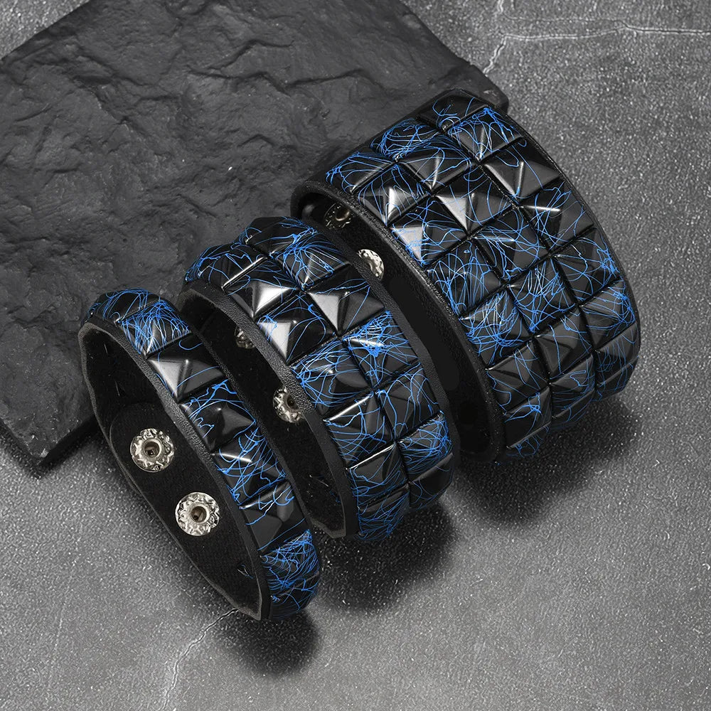 Black leather bracelets with blue stitching and silver studs on a dark surface