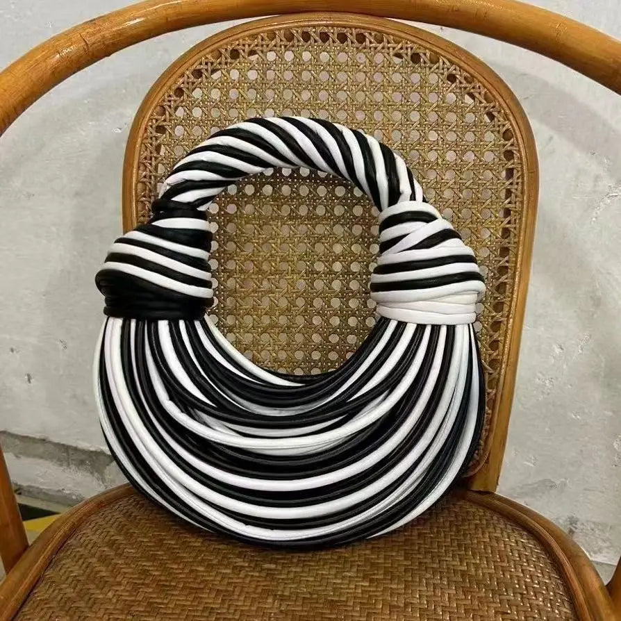A black and white noodle design handbag placed on a chair.