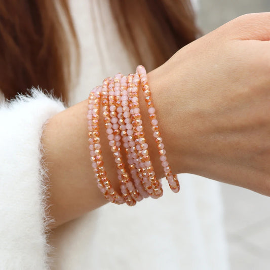 Close-up of a wrist wearing multiple beaded bracelets on a neutral background
