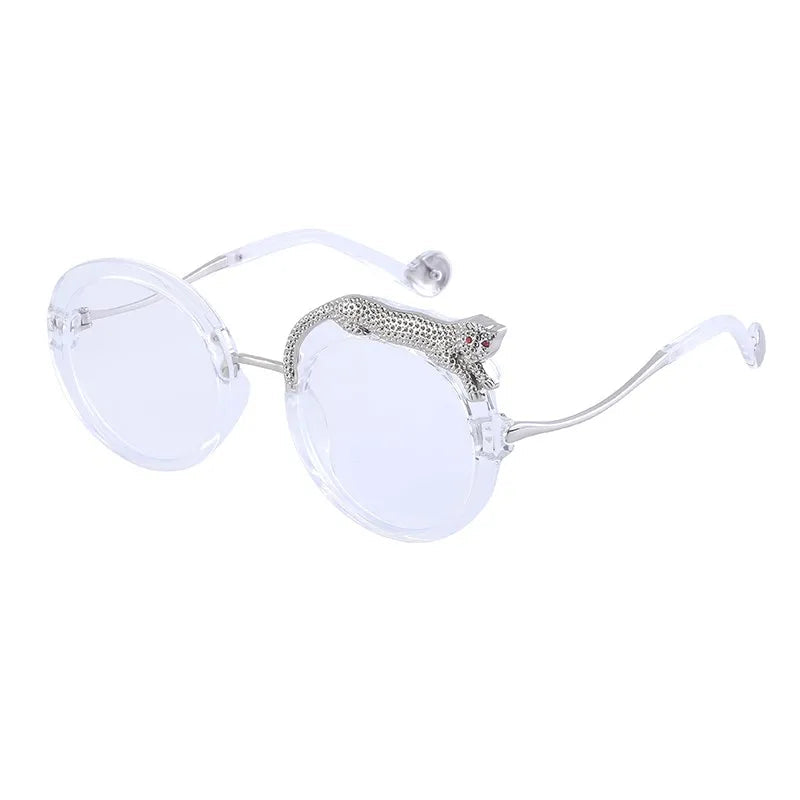 Clear sunglasses with silver leopard shape on frame on a white background.