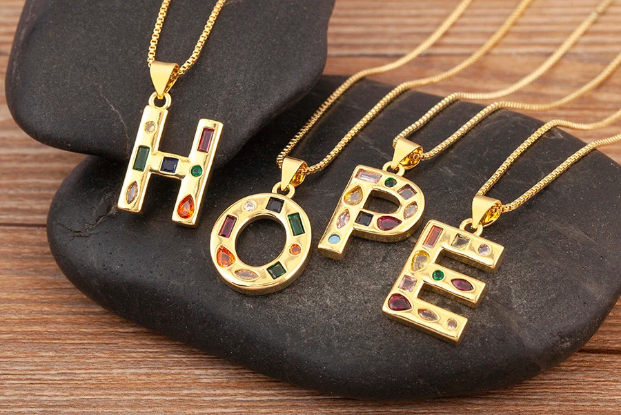 Gold necklaces with 'HOPE' pendants on a dark stone surface