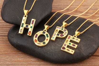 Gold necklaces with 'HOPE' pendants on a dark stone surface