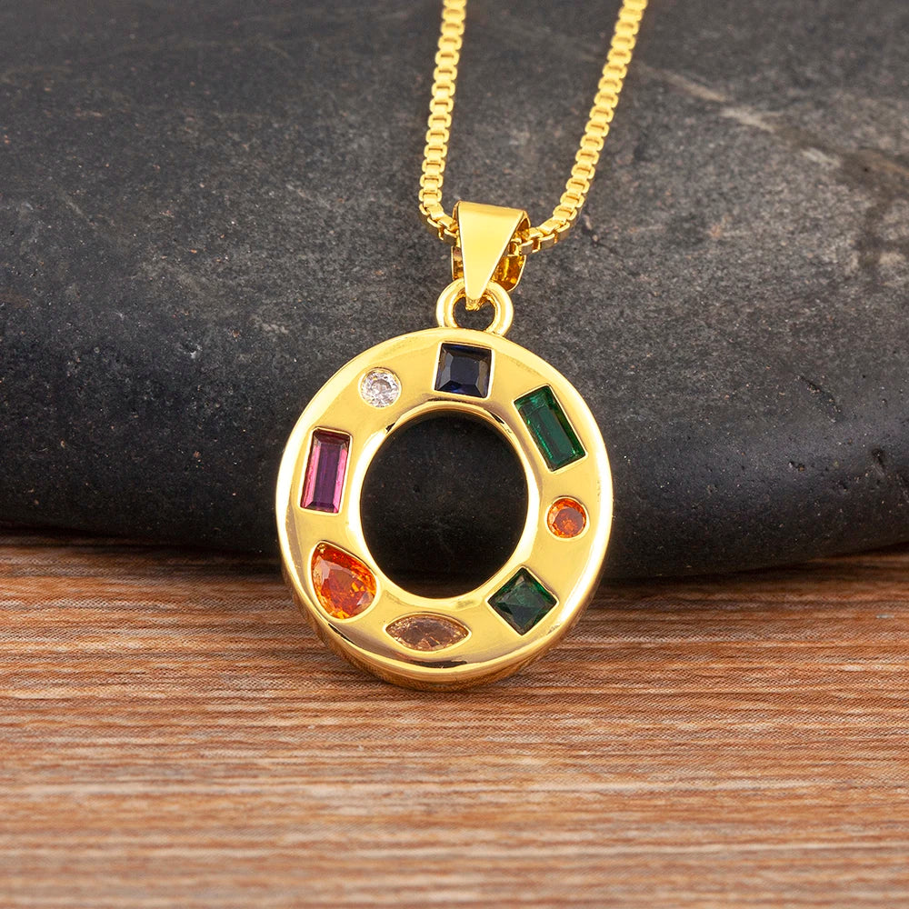 Gold necklace with a circular pendant featuring coloured stones on a wooden surface.