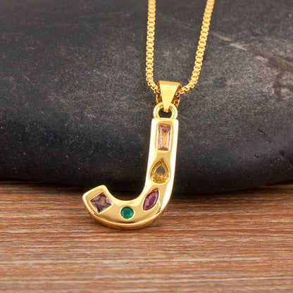 Gold pendant with colourful stones on a chain against a dark stone background