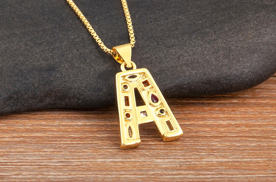 Gold necklace with a letter 'A' pendant on a wooden surface