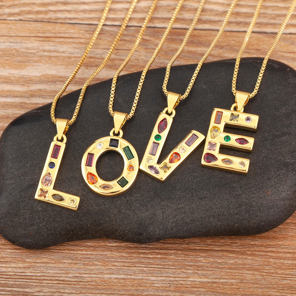 Gold necklaces with 'LOVE' pendants on a dark stone surface