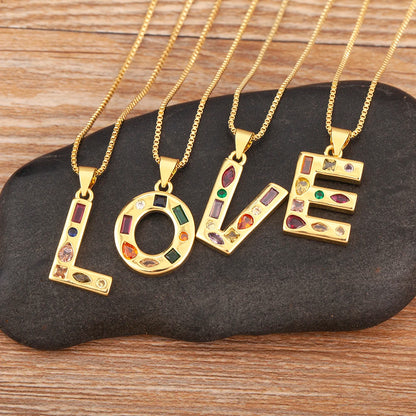 Gold necklaces with 'LOVE' pendants on a dark stone surface
