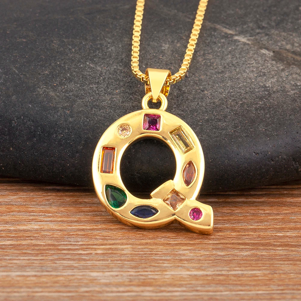 Gold necklace with a circular pendant featuring colourful gemstones on a wooden surface.