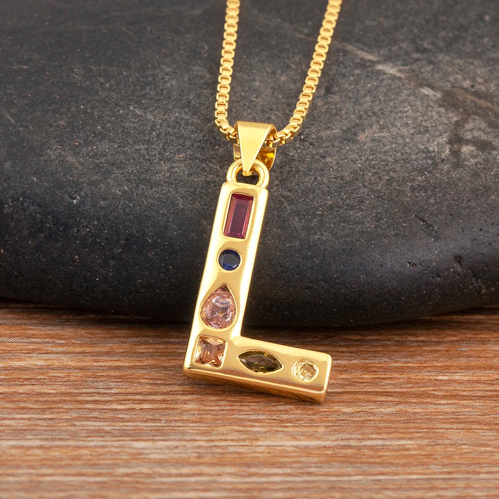 Gold necklace with a pendant featuring coloured stones on a dark stone and wooden surface.