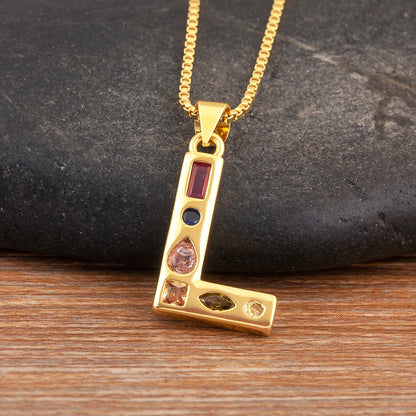 Gold necklace with a pendant featuring coloured stones on a dark stone and wooden surface.