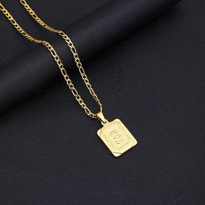 Gold necklace with a square pendant on a black fabric background