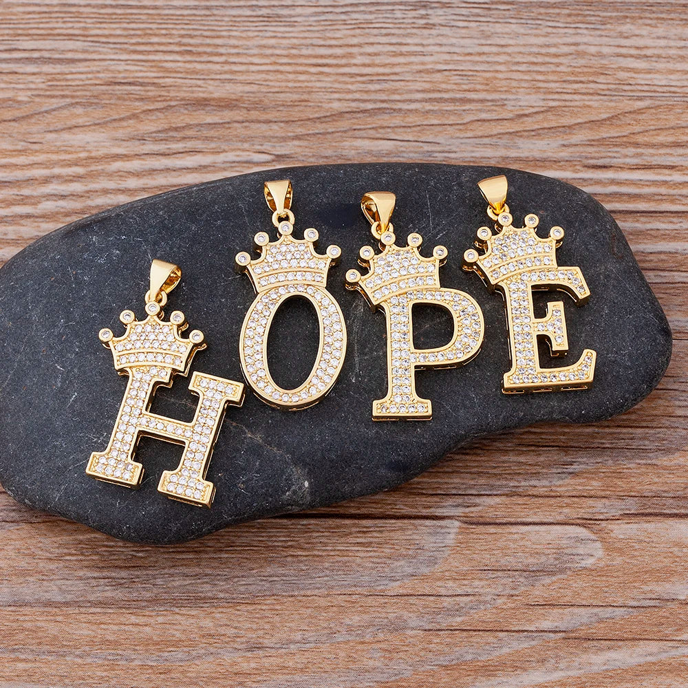 Gold 'HOPE' pendants with crowns on a dark stone surface
