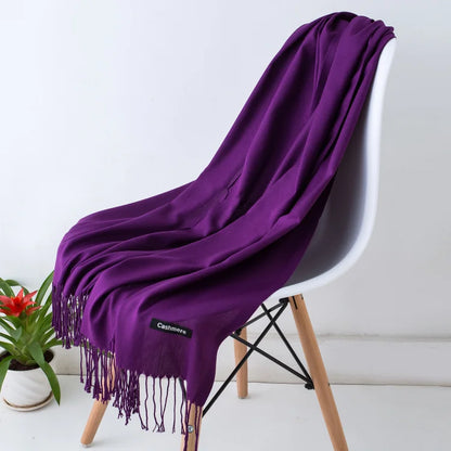 Purple cashmere scarf draped over a white chair with a plant in the background