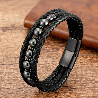 Black braided leather bracelet with shiny black beads on a wooden surface