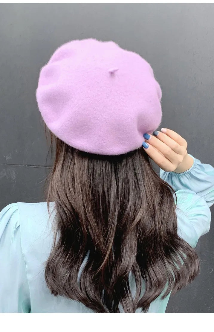 Person wearing a light purple beret against a grey background