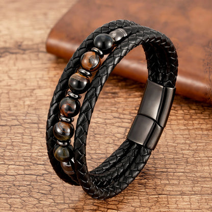 Black braided leather bracelet with black and brown beads and clasp on a wooden surface