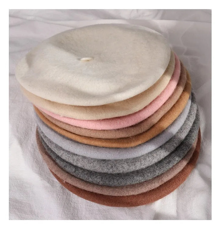 Stack of colourful berets on a white fabric background