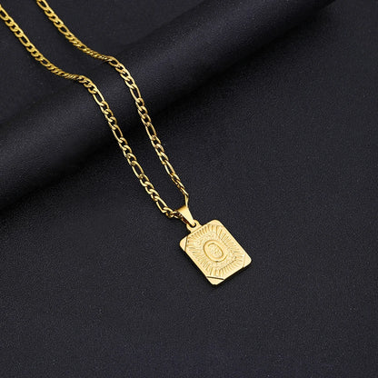 Gold necklace with a square pendant on a black fabric background