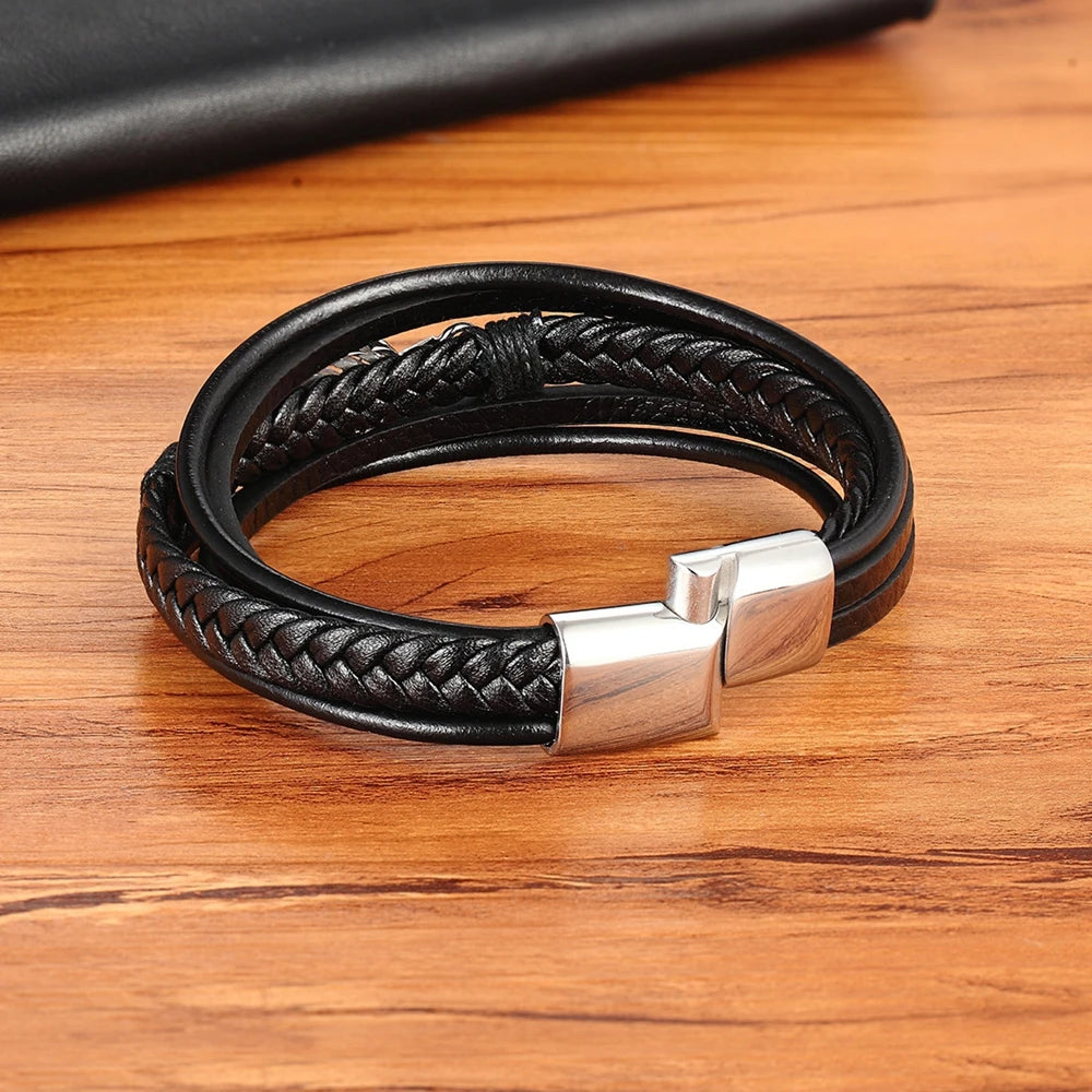 Black braided leather bracelet with a silver clasp on a wooden surface
