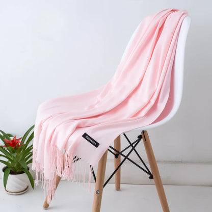 Pink scarf draped over a white chair with a plant in the background