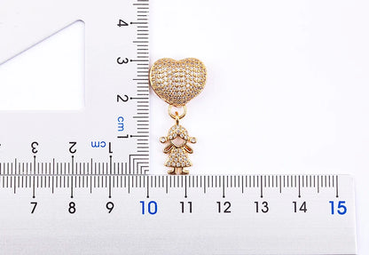 Gold heart-shaped pendant with a small figure on a white background with a ruler for scale.