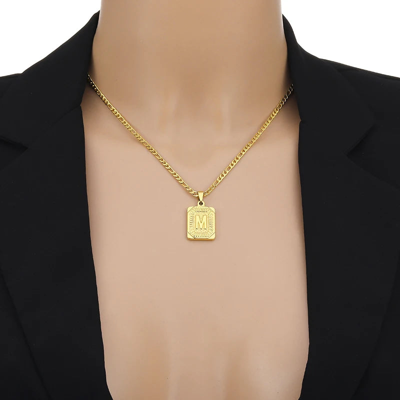 Gold necklace with a pendant on a mannequin wearing a black blazer.