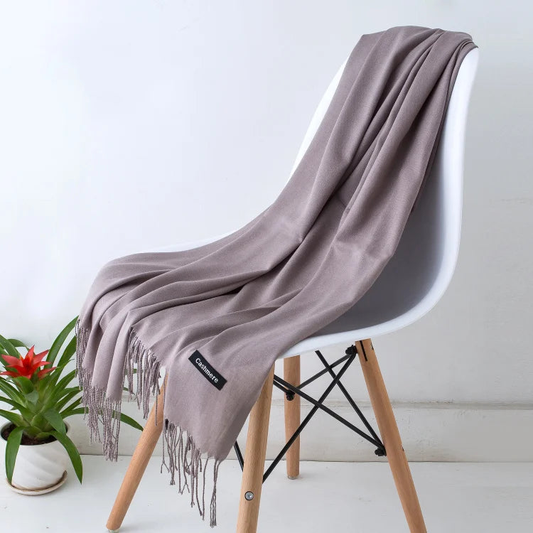 Grey scarf draped over a chair with a plant in the background
