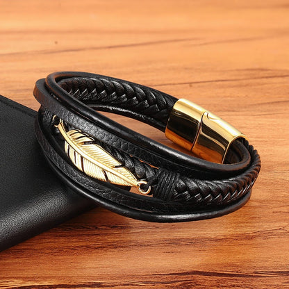 Black leather bracelet with gold feather charm and clasp on a wooden surface