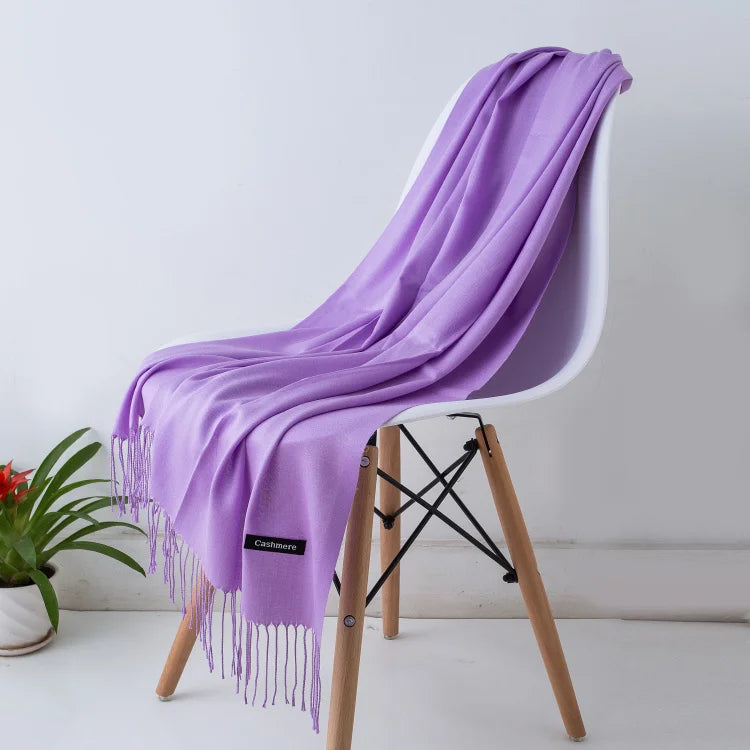 Purple scarf draped over a white chair with a visible brand label, against a light grey background.