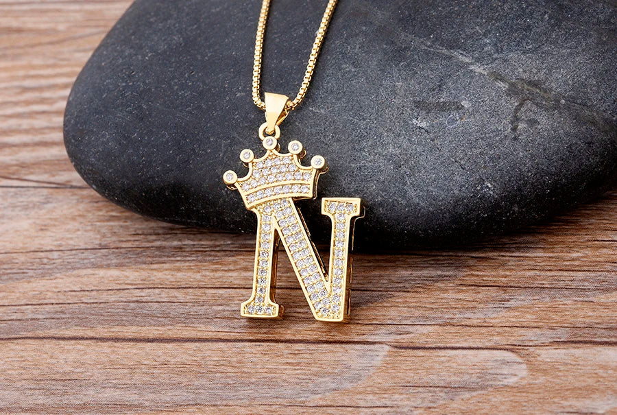 Gold necklace with a letter 'N' pendant on a wooden surface