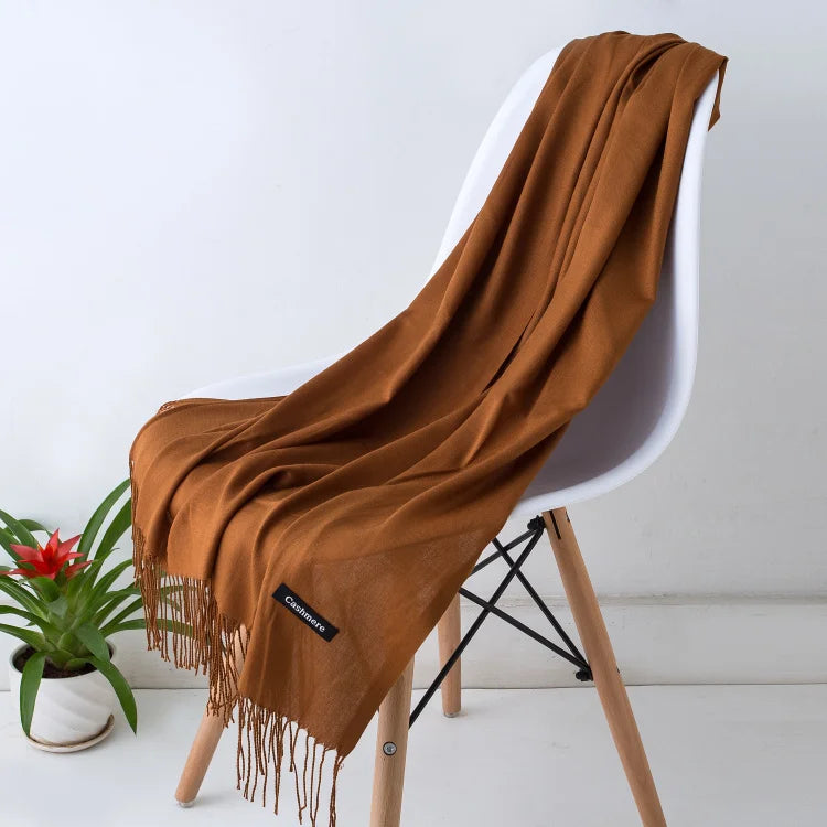 Brown blanket draped over a white chair with a plant in the background