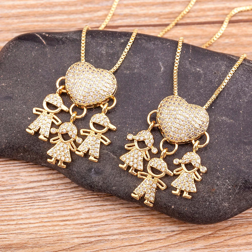 Gold necklaces with heart and child charms on a dark stone surface