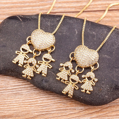 Gold necklaces with heart and child charms on a dark stone surface