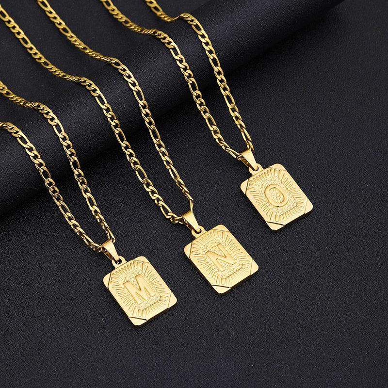 Three gold necklaces with square pendants on a black background