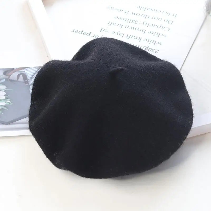 Black beret on a white surface with a magazine underneath