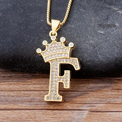 Gold necklace with a letter 'F' pendant on a dark surface
