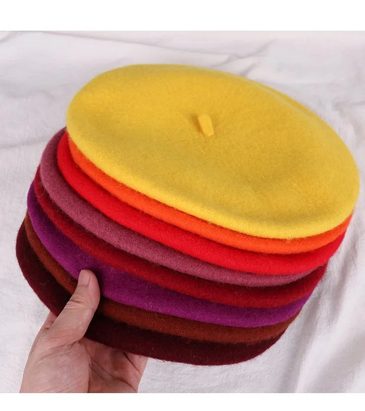 Stack of colourful berets held by a hand on a white background