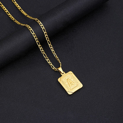 Gold necklace with a square pendant on a black fabric background