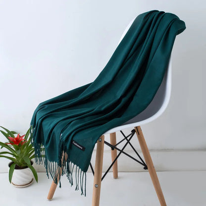 Teal blanket draped over a white chair with a plant in the background
