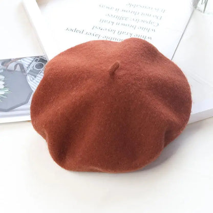 Caramel beret on a white surface with a magazine in the background