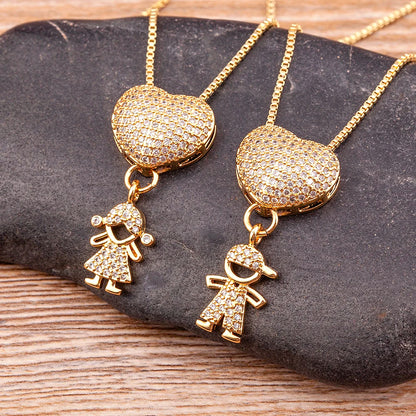 Gold heart-shaped pendants with child and baby charms on a stone surface